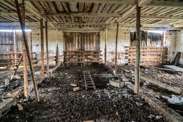 Vista interna della stalla del fienile in rovina abbandonata Il vecchio fienile abbandonato con i resti del fienile degli alimentatori dall'interno con poca luce