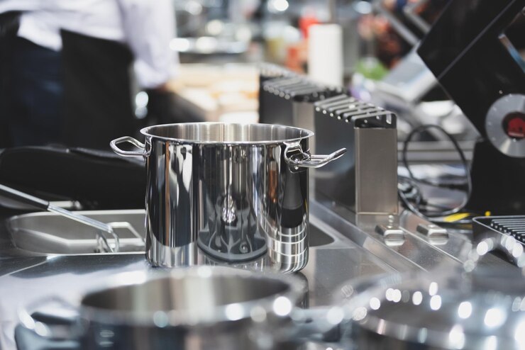 Vista interna di una cucina professionale in un ristorante o hotel con focus selettivo su pentole in acciaio inossidabile