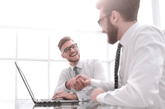 Vista laterale colleghi di lavoro che si stringono la mano sul posto di lavoro