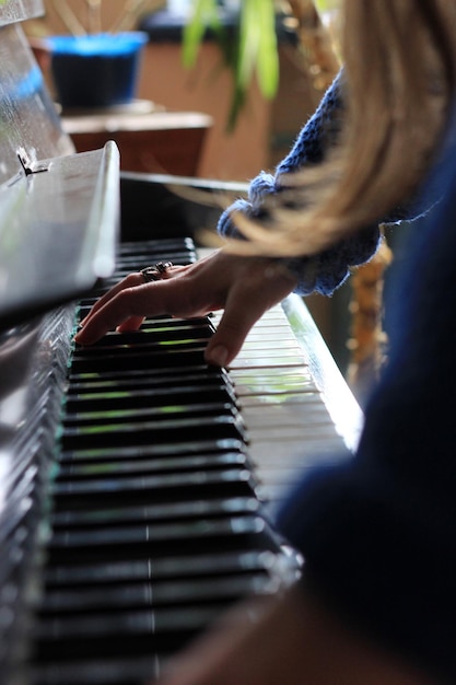 Vista laterale da vicino della mano che suona il pianoforte