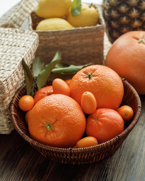 Vista laterale degli agrumi come merce nel carrello del kumquat del mandarino arancione con il cestino dell'ananas dei limoni su fondo di legno