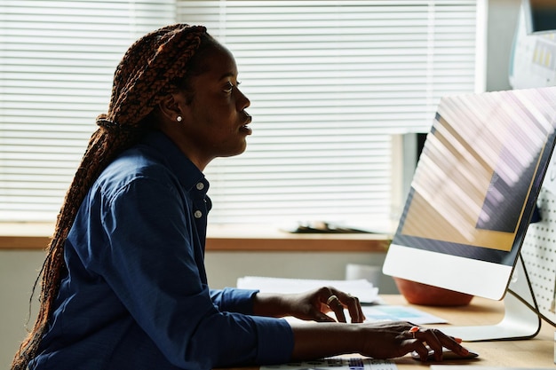 Vista laterale del giovane dipendente afroamericano dal posto di lavoro