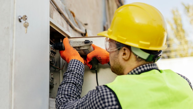 Vista laterale del lavoratore di sesso maschile con giubbotto riflettente e cappello duro
