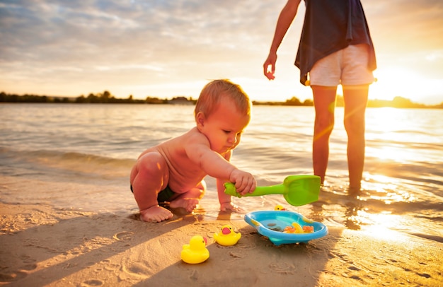 Vista laterale del piccolo bambino adorabile che gioca con le anatre gialle di gomma minuscole nella piccola piscina blu