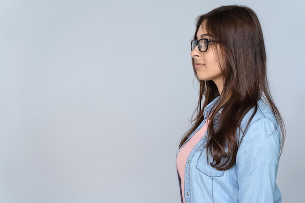 Vista laterale del profilo di una giovane donna indiana con gli occhiali isolata su uno sfondo grigio