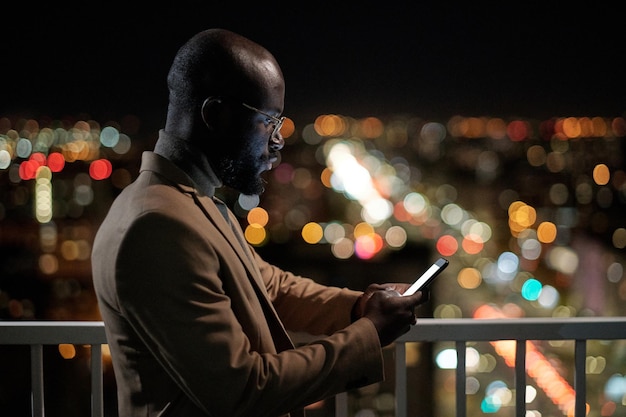 Vista laterale dell'uomo d'affari africano con smartphone