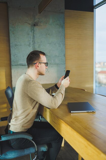 Vista laterale dell'uomo d'affari maschio in abiti casual preoccupato per gli affari appoggiati al tavolo nella sala conferenze dell'ufficio moderno