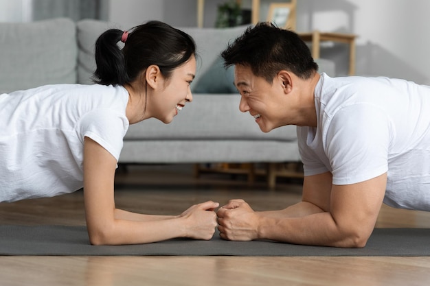 Vista laterale dell'uomo e della donna asiatici sportivi che fasciano insieme