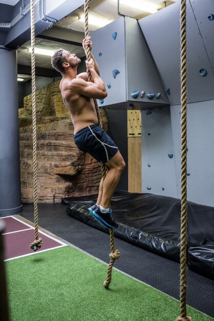 Vista laterale dell&#39;uomo muscolare che fa arrampicata su corda