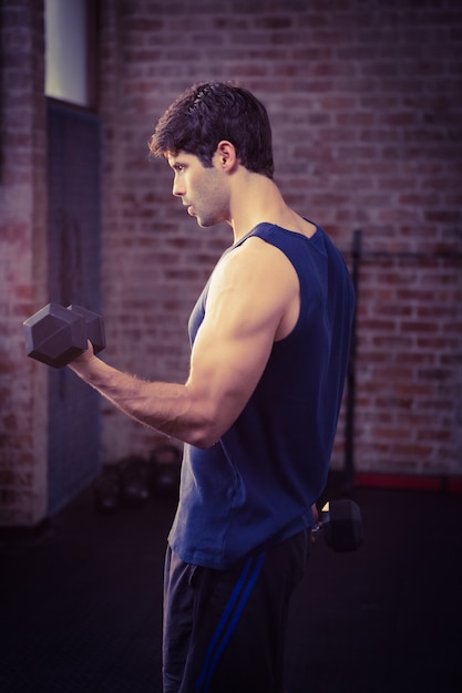 Vista laterale dell&#39;uomo serio che alza i dumbbells