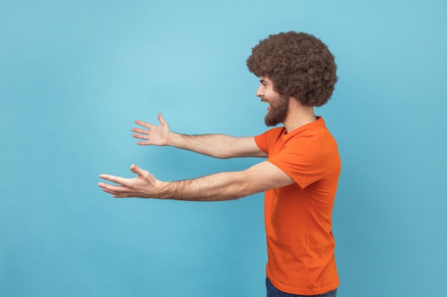 Vista laterale dell'uomo soddisfatto con l'acconciatura afro che si allunga verso la telecamera che allunga le braccia per abbracciarti