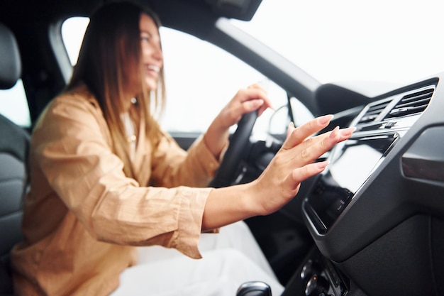 Vista laterale della bella giovane donna alla moda che è dentro la sua automobile moderna