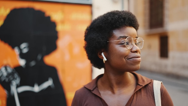 Vista laterale della donna afroamericana attraente con gli occhiali che guardano h