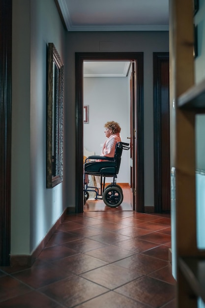 Vista laterale della donna anziana sola in sedia a rotelle