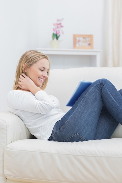 Vista laterale della donna casuale che utilizza compressa digitale sul sofà