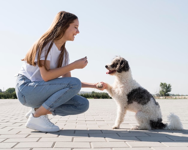 Vista laterale della donna che tiene la zampa del cane