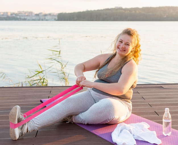 Vista laterale della donna formazione con elastico in riva al lago