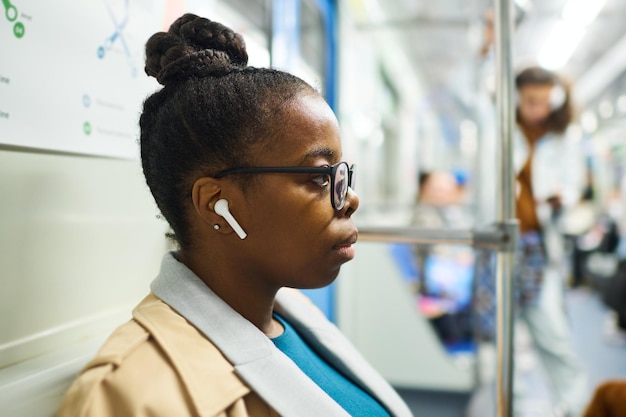 Vista laterale della giovane donna afroamericana seria in occhiali e abbigliamento casual