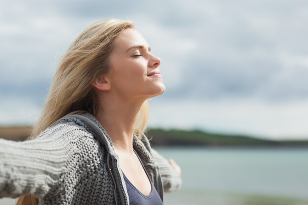 Vista laterale della giovane donna che allunga le sue braccia sulla spiaggia