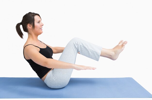 Vista laterale della giovane donna che si esercita sulla stuoia di yoga