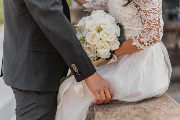 Vista laterale della sposa e dello sposo con bouquet di fiori