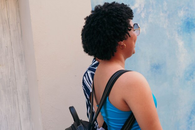Vista laterale delle donne con acconciatura afro e occhiali che camminano per strada.