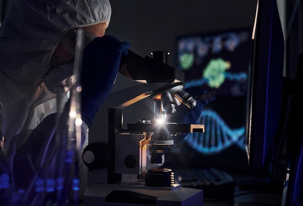 Vista laterale dello scienziato in uniforme protettiva bianca che lavora con coronavirus in laboratorio