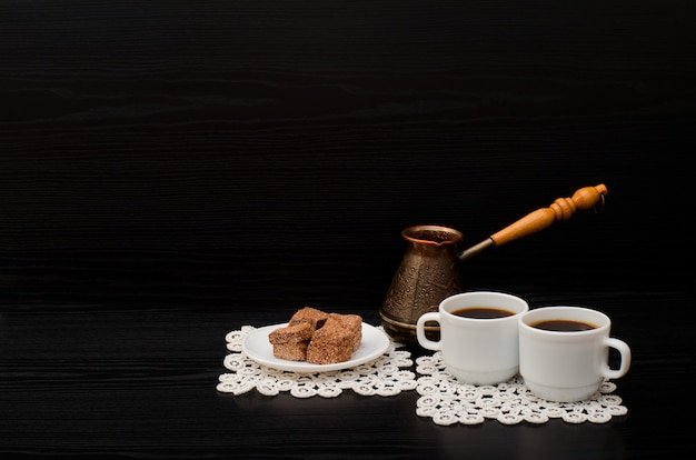 Vista laterale di due tazze di caffè sui tovaglioli di pizzo, dessert al cioccolato e vasi turchi