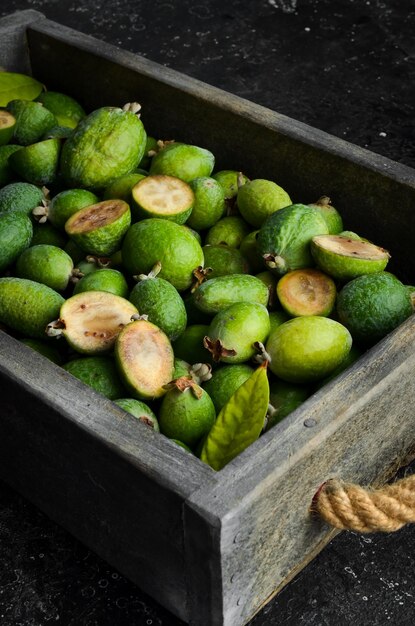 Vista laterale di feijoas verdi fresche naturali, su sfondo di pietra nera.