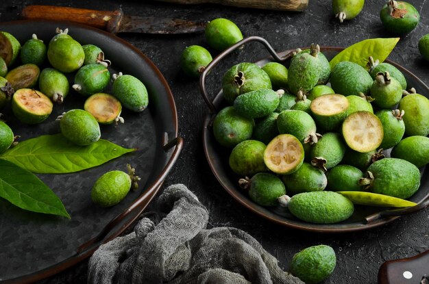 Vista laterale di feijoas verdi freschi naturali su sfondo di pietra nera