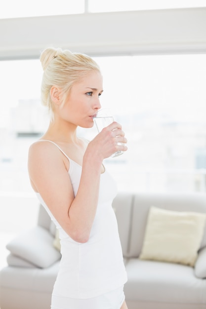 Vista laterale di un&#39;acqua potabile della donna di misura in palestra