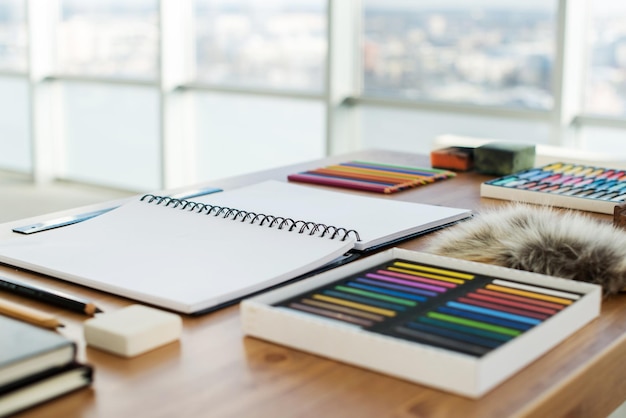 Vista laterale di un'area di lavoro di un pittore Scrivania in legno con strumenti artistici preparati per il disegno a pastello