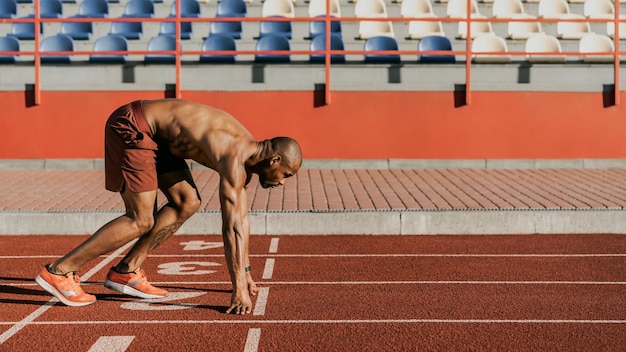 Vista laterale di un atleta che si prepara a iniziare il suo sprint su una pista da corsa