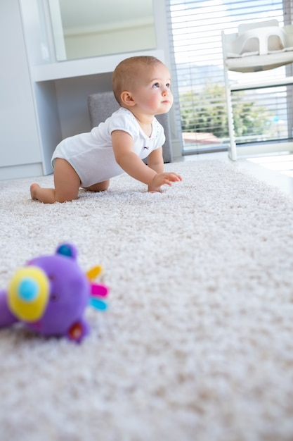 Vista laterale di un bambino che striscia sul tappeto