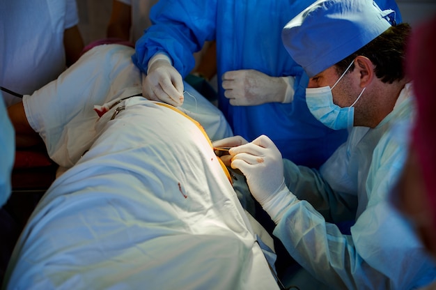 Vista laterale di un chirurgo che sutura una ferita utilizzando uno strumento chirurgico