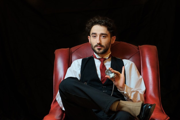 Vista laterale di un giovane uomo d'affari elegante che fuma una sigaretta su sfondo nero studio Primo piano
