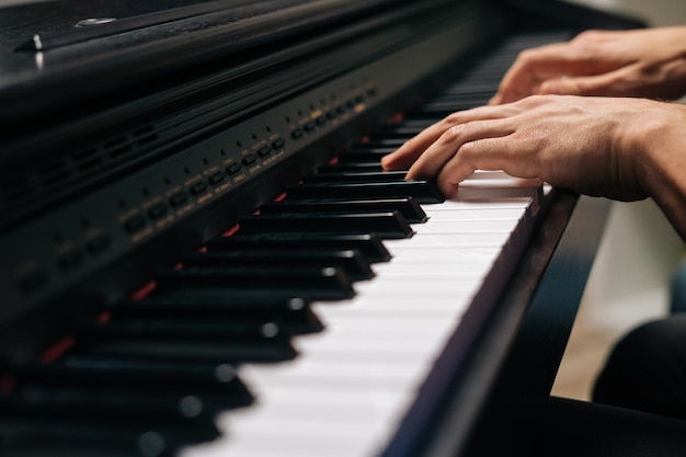 Vista laterale di un musicista irriconoscibile che suona sintetizzando in studio a casa durante la lezione