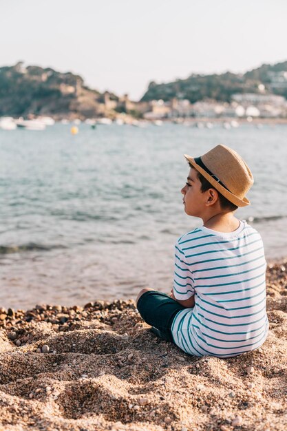 Vista laterale di un ragazzo seduto sulla spiaggia