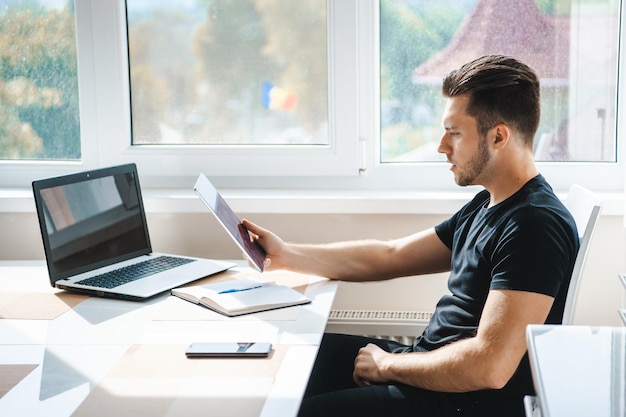 Vista laterale di un uomo d'affari che tiene tablet uomo d'affari che lavora a casa smart working con tablet e...