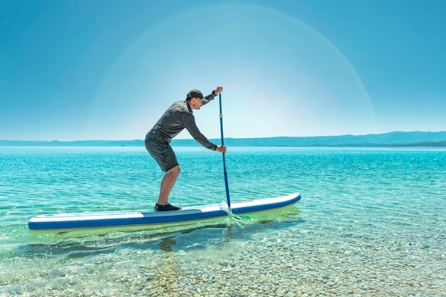 Vista laterale di un uomo maturo che fa paddleboard sul lago