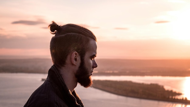 Vista laterale di un uomo riflessivo contro il mare durante l'alba