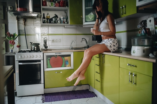 Vista laterale di una donna che beve caffè mentre è seduta in cucina
