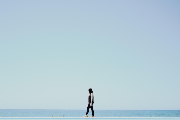 Vista laterale di una donna che cammina sul mare