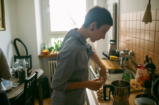 Vista laterale di una donna che cucina in cucina a casa