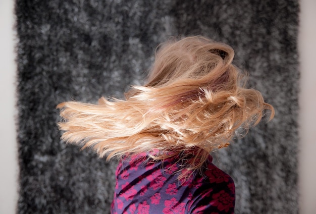 Vista laterale di una donna che getta i capelli biondi