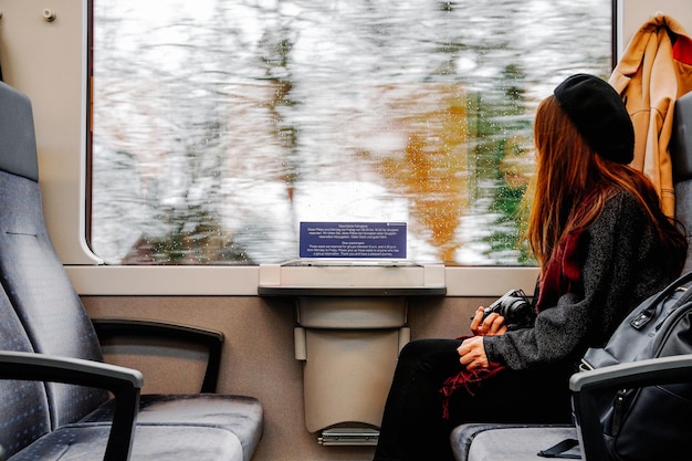 Vista laterale di una donna con una fotocamera che viaggia in treno