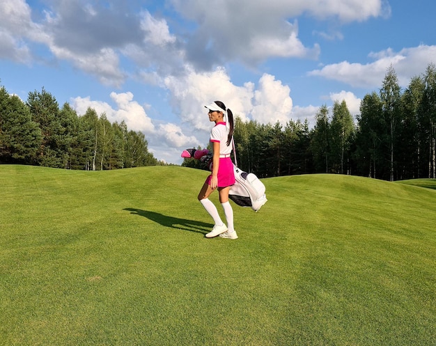 Vista laterale di una donna con una sacca da golf che cammina sul campo da golf