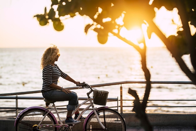 Vista laterale di una donna in bicicletta sul mare contro il cielo