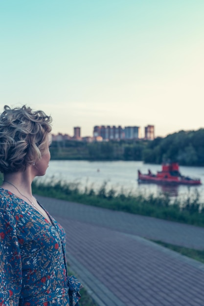 Vista laterale di una donna in piedi contro il fiume in città