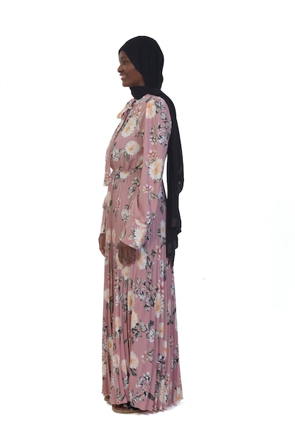 Vista laterale di una donna in piedi e vestito e burka su sfondo bianco